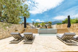 a patio with three lounge chairs and a pool at Archontiki Elite Villa - Private Pool, Chania in Vryses