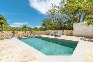 a swimming pool with chairs and a stone wall at Archontiki Elite Villa - Private Pool, Chania in Vryses