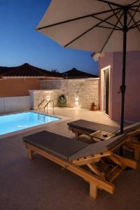 a swimming pool with an umbrella and a table and a pool at Lux Studios With Private Pool by ILIOS Georgioupoli in Georgioupoli