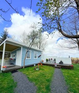 a blue house with a porch and a yard at Baksas Luxury Campers in Selfoss +17 photos