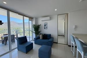 a living room with blue chairs and a table at Ocean Club by Colproperty Management in Playa Bello Horizonte