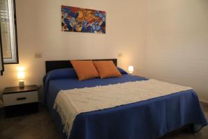 a bedroom with a blue bed with two orange pillows at House Mimma Tropea in Santa Domenica