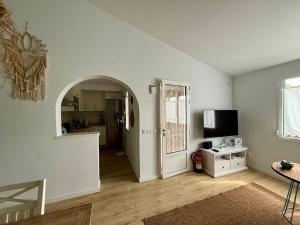 a white living room with an archway and a television at Xalet Son Favaritx by GMHouse Menorca in Cala en Bosc