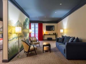 a living room with a blue couch and a bedroom at Mercure Bordeaux Chateau Chartrons in Bordeaux