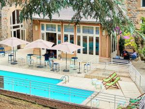 a swimming pool with tables and umbrellas and chairs at Mercure Saint Nectaire - Spa & Bien-Être in Saint-Nectaire