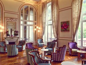 a room with chairs and tables and windows at Mercure Saint Nectaire - Spa & Bien-Être in Saint-Nectaire