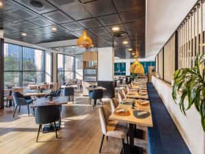a restaurant with tables and chairs and windows at Novotel Genova City in Genoa