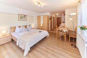 a bedroom with a white bed and a desk and a table at Gästehaus Gruber in Piding
