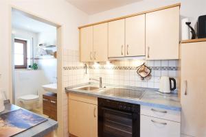 a kitchen with white cabinets and a sink at Gästehaus Gruber in Piding +25 photos