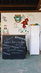 a sign in front of a wall with a flower on it at Kombi Hostel Camping in Vale do Capao