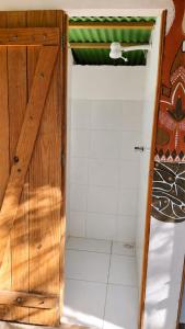a bathroom with a shower with a wooden door at Kombi Hostel Camping in Vale do Capao +46 photos