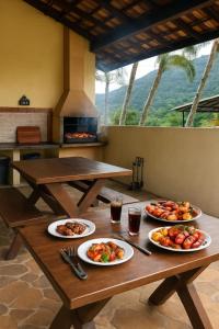 a wooden table with plates of food on it at Refugio e Fortaleza in Ubatuba