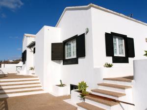 Casa blanca con ventanas con persianas negras y escaleras en Villa Angela, en Mácher