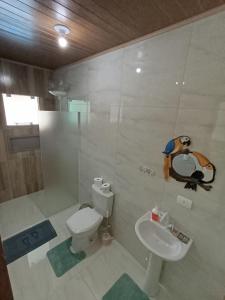 a bathroom with a white toilet and a sink at Reino Encantado Dona Siroba in Morretes +8 photos