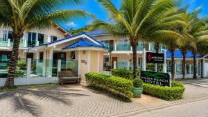 a hotel with palm trees in front of a building at Paúba Beach Hotel in Pauba
