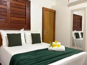 a white bed with a green blanket and flowers on it at Chalés Refúgio Fortim in Fortim