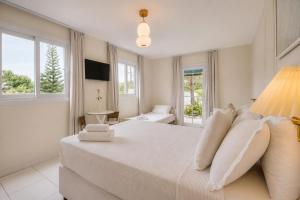 a white bedroom with a large bed and windows at Elsi Pousada in Búzios +74 photos