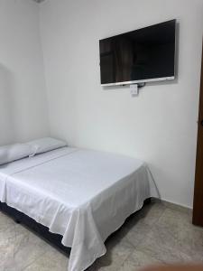 a bedroom with a bed with a flat screen tv on the wall at Hotel San Luis in Buga