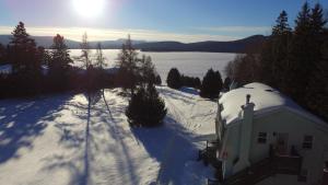 a house in the snow next to a body of water at Motel Le Fleuron in Saint-Donat-de-Montcalm