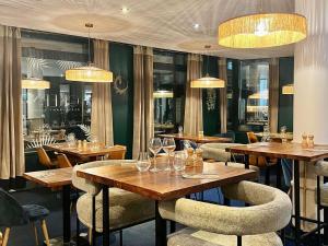 a restaurant with wooden tables and chairs and chandeliers at Novotel Paris Pont De Sevres in Sèvres