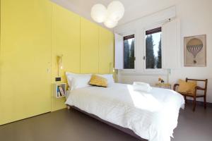 a bedroom with a white bed and a yellow wall at Mòsì Firenze in Florence