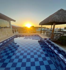 a swimming pool with a sunset in the background at Pousada Bugaendrus in Touros