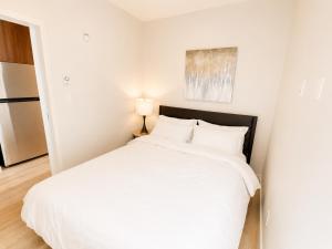 a bedroom with a white bed and a refrigerator at Lovely Brand New Suite in Sidney
