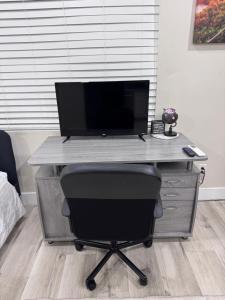 a computer desk with a monitor and a chair at Private Studio, Near DT & Cal Expo, Free Parking in Sacramento