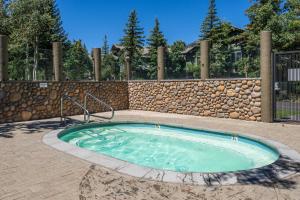 a hot tub in a patio with a stone wall at Snowcreek V 883 in Mammoth Lakes