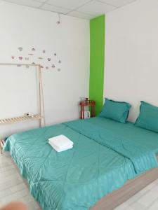 a green bed in a white room with a green wall at Hom Ba cây dừa in Vĩnh Hy
