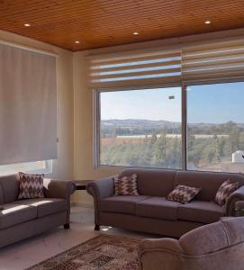 a living room with two couches and a large window at مزرعة اننتارا in Amman