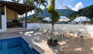 a patio with chairs and umbrellas next to a pool at Refugio e Fortaleza in Ubatuba
