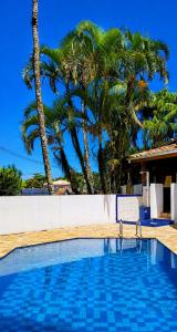 a swimming pool with a chair next to palm trees at Refugio e Fortaleza in Ubatuba