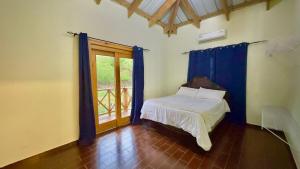 a bedroom with a bed with blue curtains and a window at Villa Ana Rosa in Jarabacoa