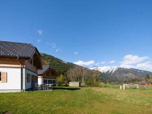a house in a field with mountains in the background at Haus am Bach in Donnersbachwald