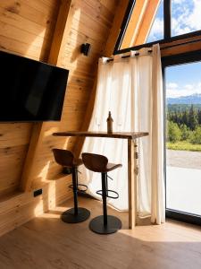 a table and two stools in a room with a large window at Jugoslavija Chalet and Spa Zabljak in Tepačko Polje