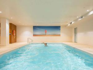 a person swimming in a indoor swimming pool at Novotel Melbourne Glen Waverley in Glen Waverley