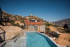 a swimming pool in front of a house with a mountain at Primario Hotel Boutique in Ensenada