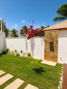 a garden with a white fence and red flowers at Villa Rita - Preá in Prea
