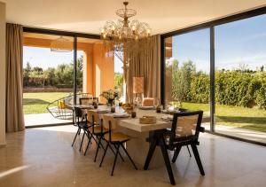 a dining room with a table with chairs and a chandelier at Villa Émeraude 5 Ch in Marrakesh