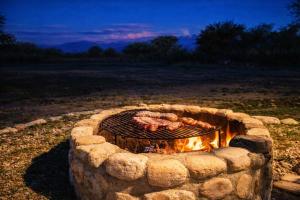 a stone fire pit with meat cooking on it at Refugio Serrano con Chimenea y Caballos in San Javier