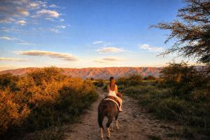 a woman riding a horse down a dirt road at Refugio Serrano con Chimenea y Caballos in San Javier