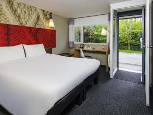 a hotel room with a bed and a desk and window at ibis Plymouth in Plymouth