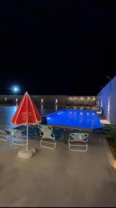 a swimming pool with a red umbrella and a blue boat at Sadeel chalet in Kerak
