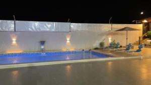 a swimming pool at night with chairs and an umbrella at Sadeel chalet in Kerak
