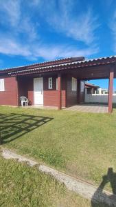 a red house with a lawn in front of it at Otima casa com 2 quartos em Tramandai in Tramandaí