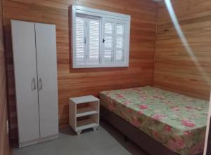 a small bedroom with a bed and a window at Otima casa com 2 quartos em Tramandai in Tramandaí