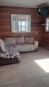a living room with a couch and a window at Otima casa com 2 quartos em Tramandai in Tramandaí