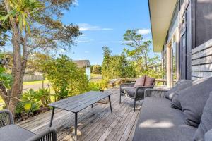 a patio with a table and chairs on a deck at Fun on the Fairway in Matarangi