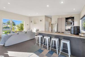 a kitchen with a bar and some stools in a room at Fun on the Fairway in Matarangi
